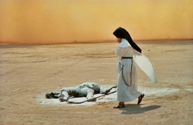 A nun passes an NVA KIA, killed during an unsuccessful attempt to free NAV prisoners of war from a nearby holding camp, Dong Lach, near Bien Hoa, Vietnam  1969 © Tim Page 
